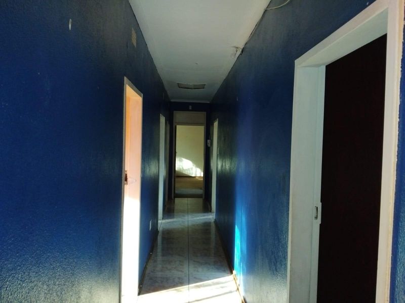 A long, empty hallway featuring tiled flooring and multiple doorways, currently finished with dark blue wall paint.