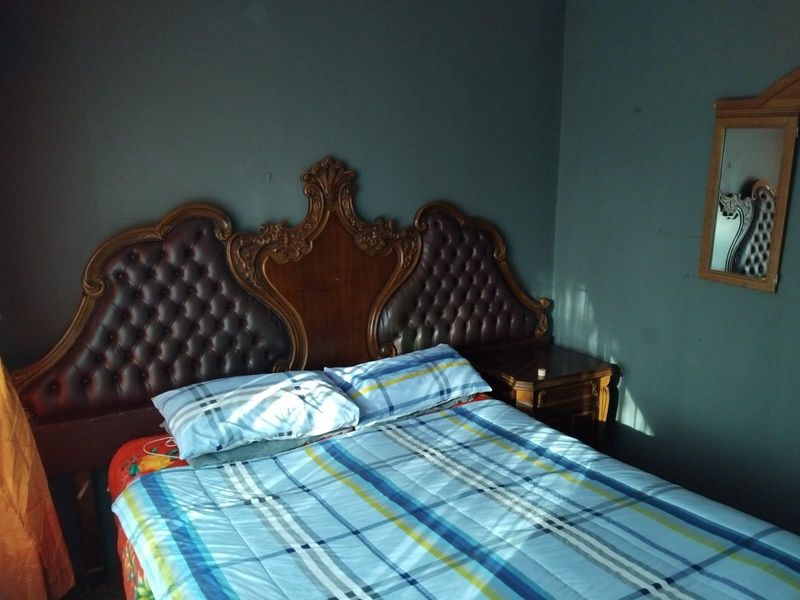 A bedroom featuring dark painted walls and a traditional wooden headboard.