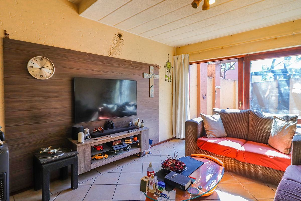 Living room featuring tiled flooring, a wood-look feature wall, and sliding glass doors providing access to the outdoor area.