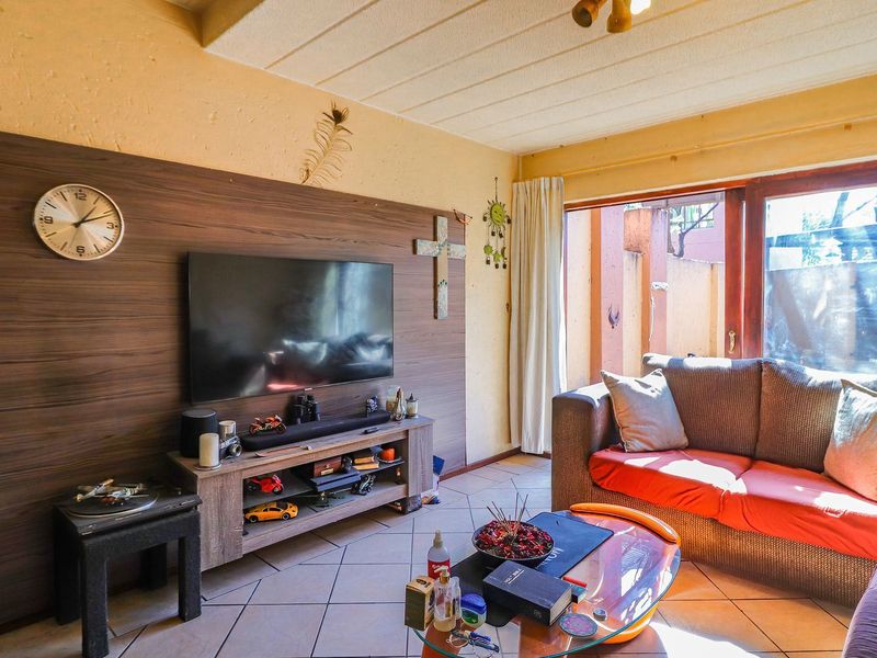 Living room featuring tiled flooring, a wood-look feature wall, and sliding glass doors providing access to the outdoor area.
