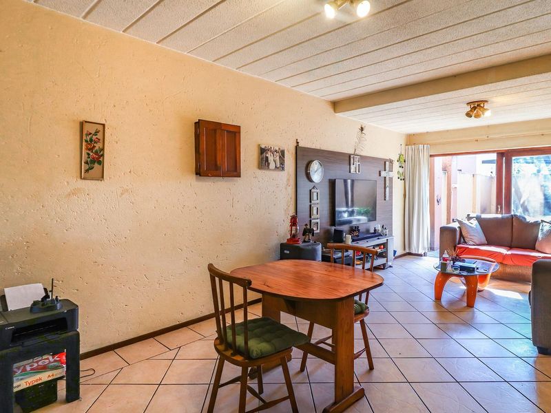 Open plan living and dining area featuring tiled flooring, textured walls, and a sliding glass door leading to an outdoor space.