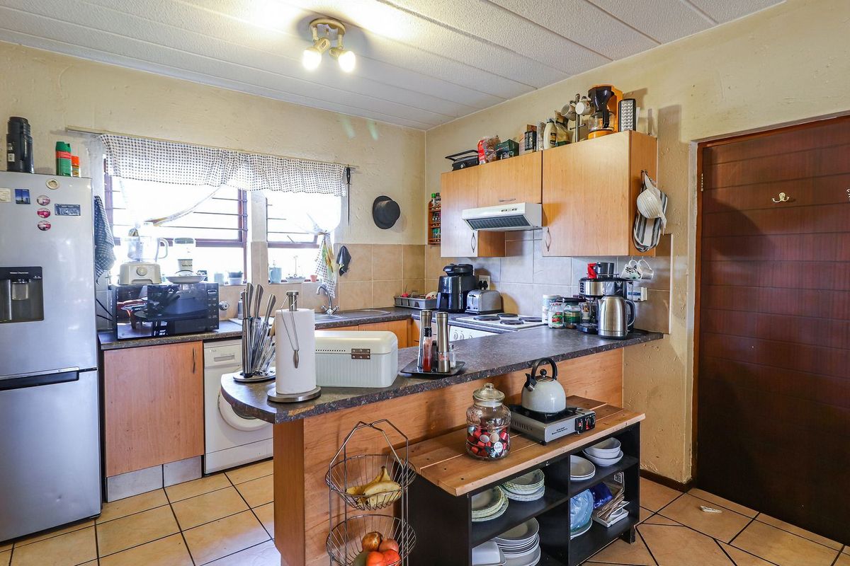 A functional kitchen featuring laminate cabinetry, a breakfast bar, tiled flooring, and a tiled backsplash, offering a practical layout for daily use.