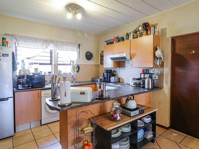 A functional kitchen featuring laminate cabinetry, a breakfast bar, tiled flooring, and a tiled backsplash, offering a practical layout for daily use.