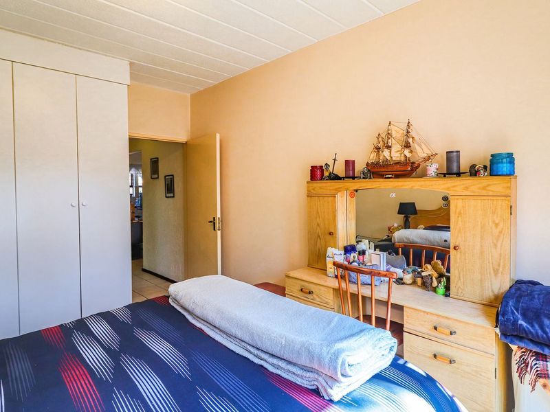 A bedroom featuring a built-in wardrobe and a textured ceiling, offering a functional space with potential for modern updates.