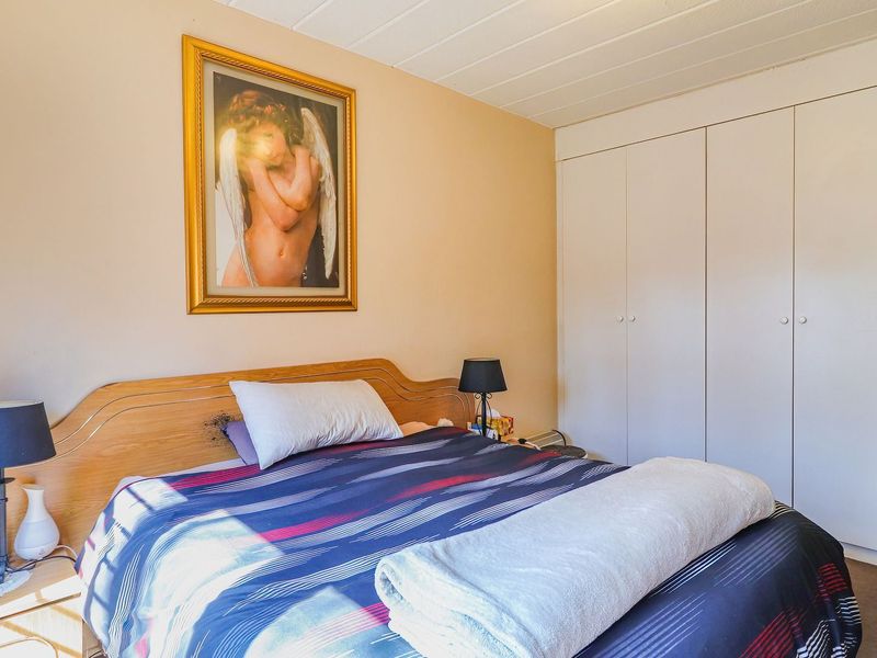 A functional bedroom featuring neutral walls, carpeted flooring, and a large built-in wardrobe providing ample storage space.