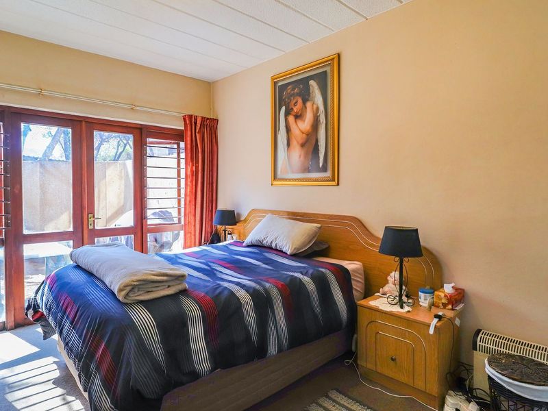 A bedroom featuring timber-framed glass sliding doors with security bars, providing natural light and access to the exterior.