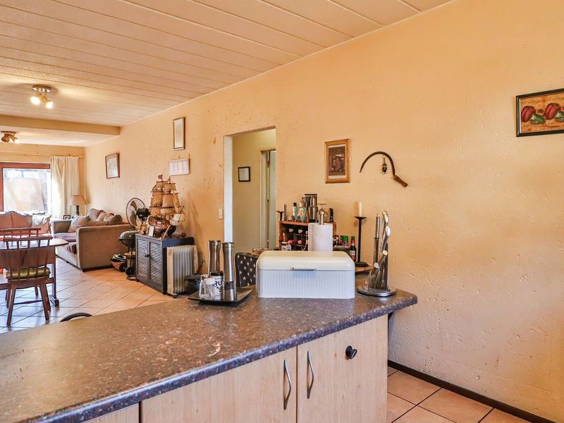 Open plan living and kitchen area featuring tiled flooring, laminate cabinetry, and direct access to an outdoor patio through sliding glass doors.