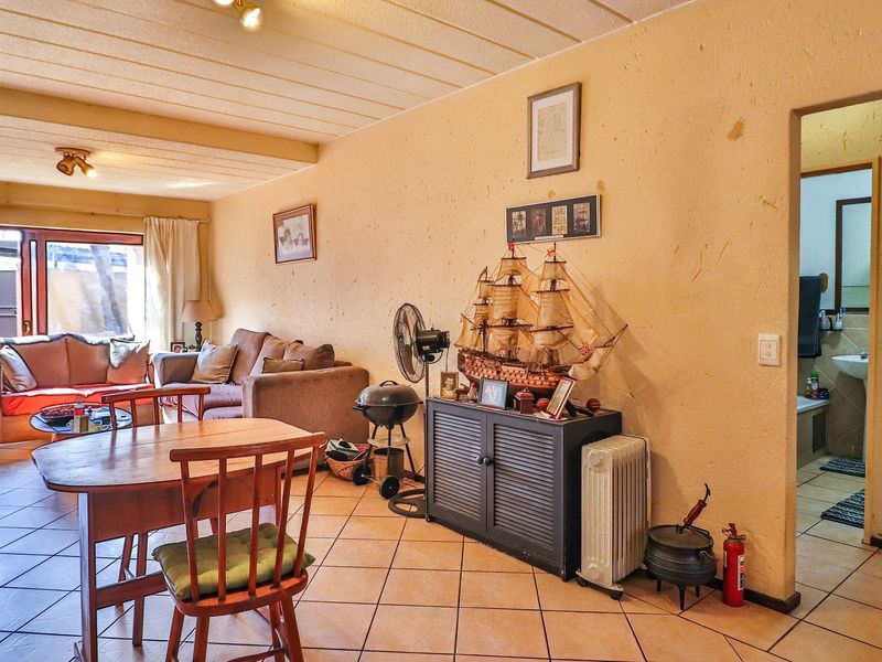 Open plan living and dining area featuring tiled flooring, textured walls, and direct access to an outdoor patio space.