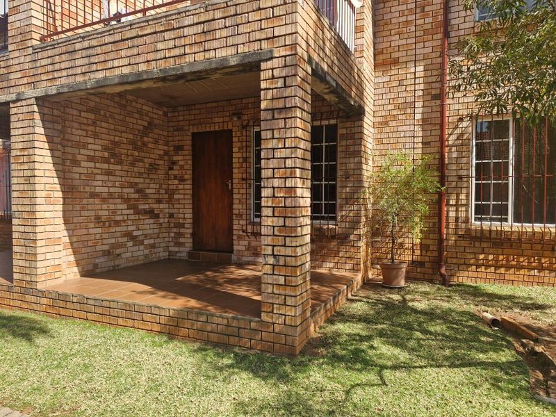 A covered ground-floor patio area featuring face brick construction, tiled flooring, and security bars on the adjacent windows.
