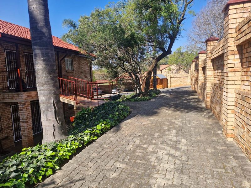 A view of the townhouse complex entrance featuring a paved driveway, facebrick exterior walls, and a metal staircase leading to the upper level.