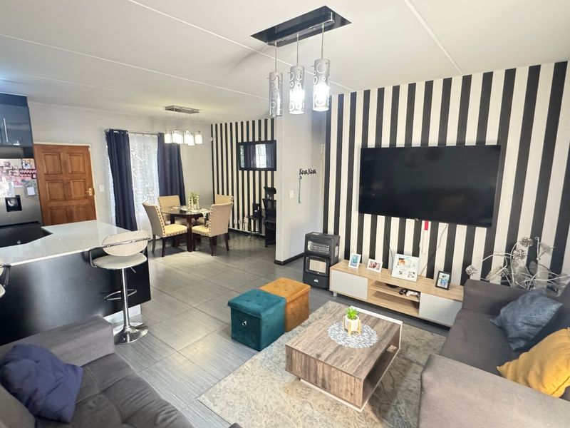 Spacious open-plan living area featuring a modern kitchen with island, tiled flooring, and integrated dining space, ideal for contemporary townhouse living.