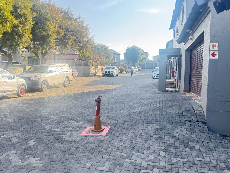 A view of the townhouse complex driveway featuring paved surfaces, garage access, and a fire hydrant.