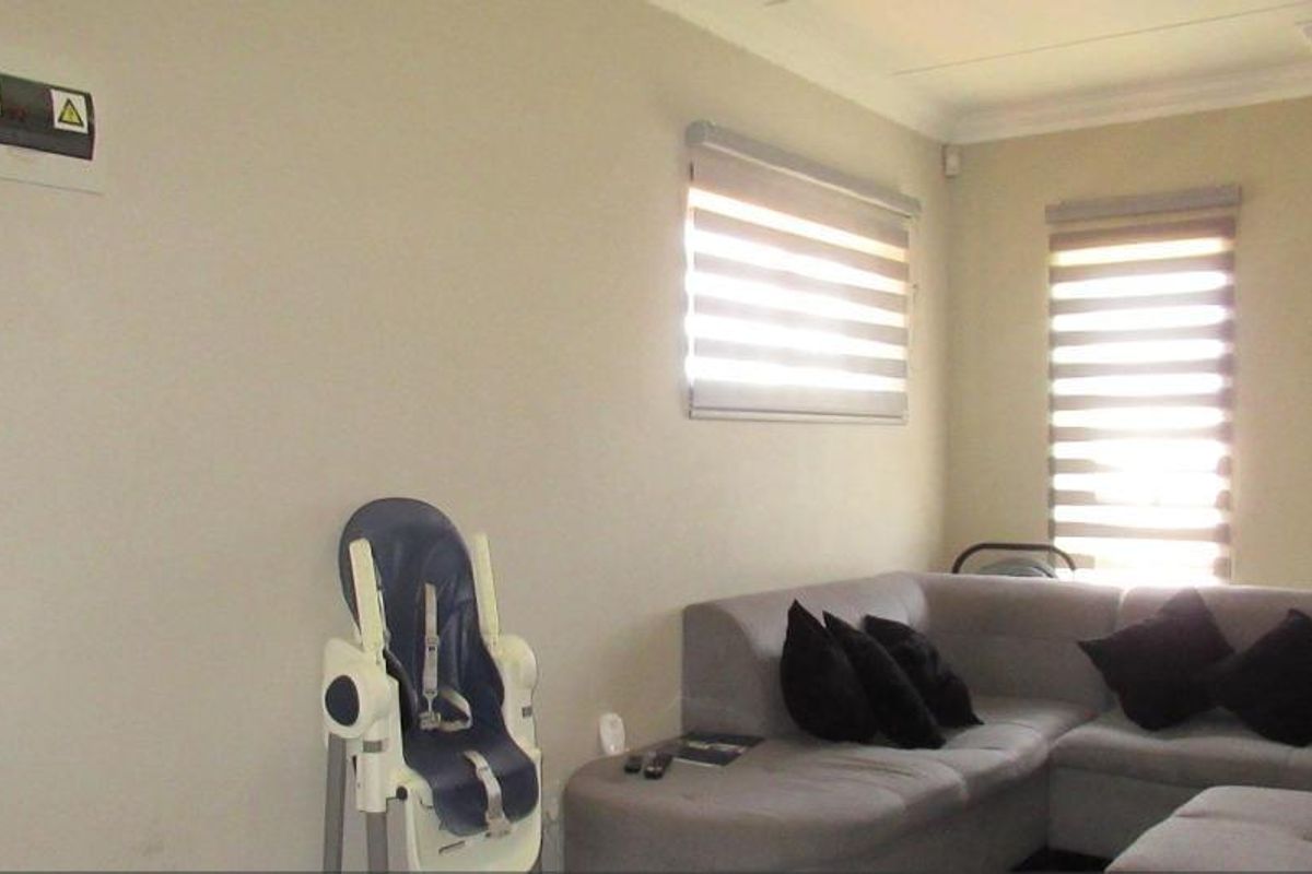 A living room featuring neutral walls, cove cornicing, and modern roller blinds, providing a clean and functional space for relaxation.