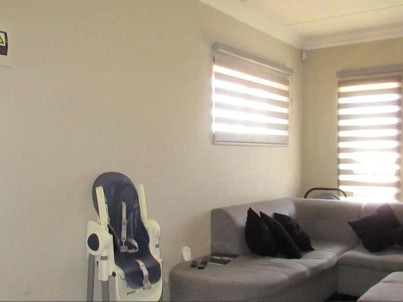 A living room featuring neutral walls, cove cornicing, and modern roller blinds, providing a clean and functional space for relaxation.