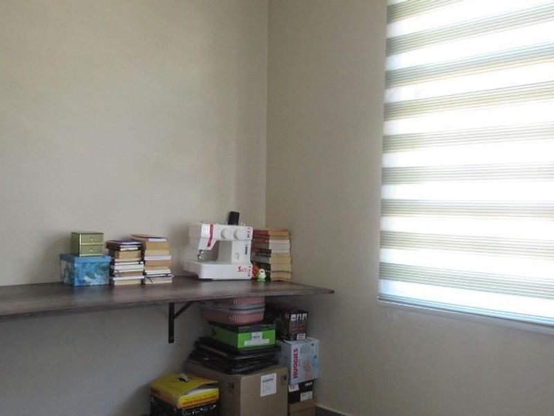 A small office space featuring a wall-mounted desk and modern zebra blinds, providing a functional area for work or study.