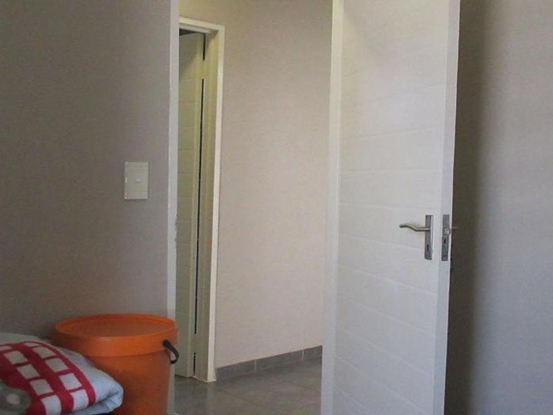 A simple interior hallway featuring tiled flooring and white internal doors, providing access between rooms.