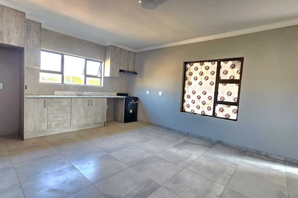 Open-plan living area featuring modern light-wood cabinetry, tiled flooring, and large windows providing ample natural light.