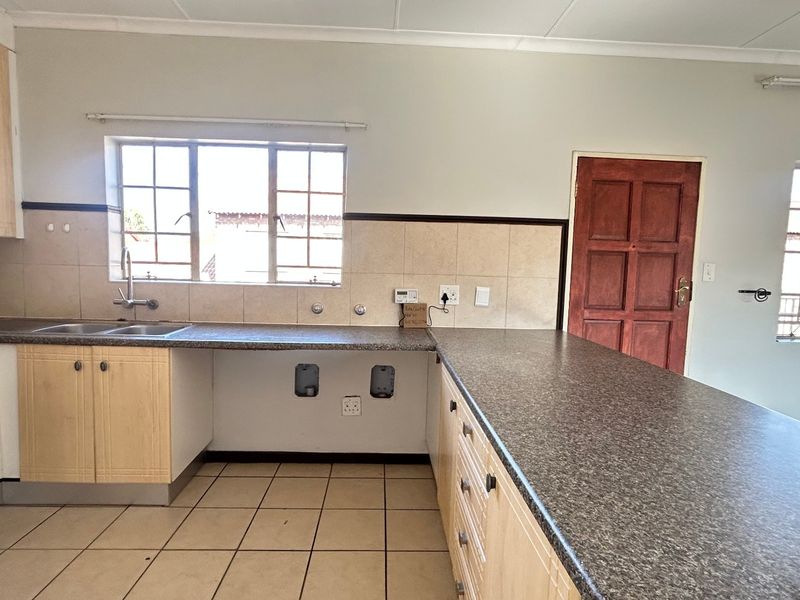A functional kitchen featuring light wood cabinetry, granite-look countertops, tiled backsplash, and ceramic flooring, offering a clean canvas for potential updates.