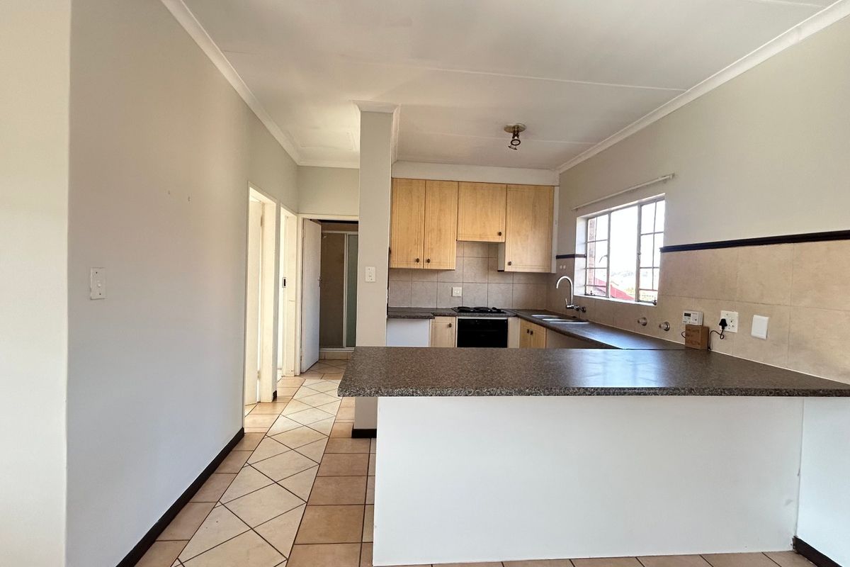 A functional kitchen featuring light wood cabinetry, laminate countertops, a breakfast bar, and tiled flooring, offering a clean and practical layout for daily use.