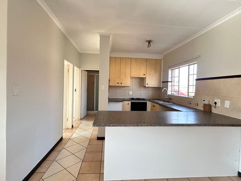 A functional kitchen featuring light wood cabinetry, laminate countertops, a breakfast bar, and tiled flooring, offering a clean and practical layout for daily use.