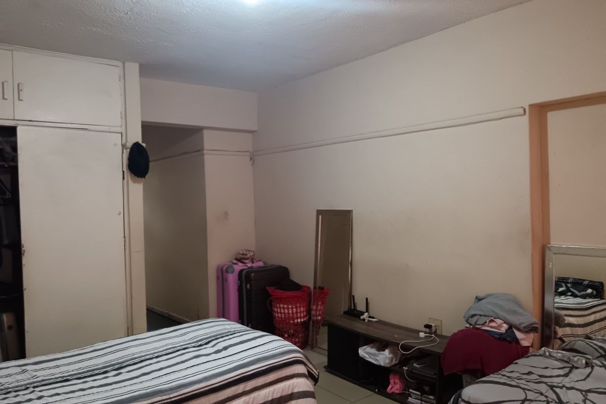 A bedroom featuring a built-in wardrobe, showing signs of wear on the ceiling and walls, suitable for renovation and cosmetic updates.