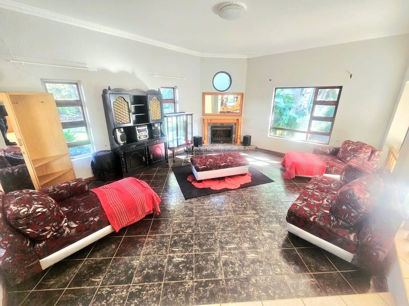 Spacious living room featuring tiled flooring, a central fireplace, and large windows providing natural light.