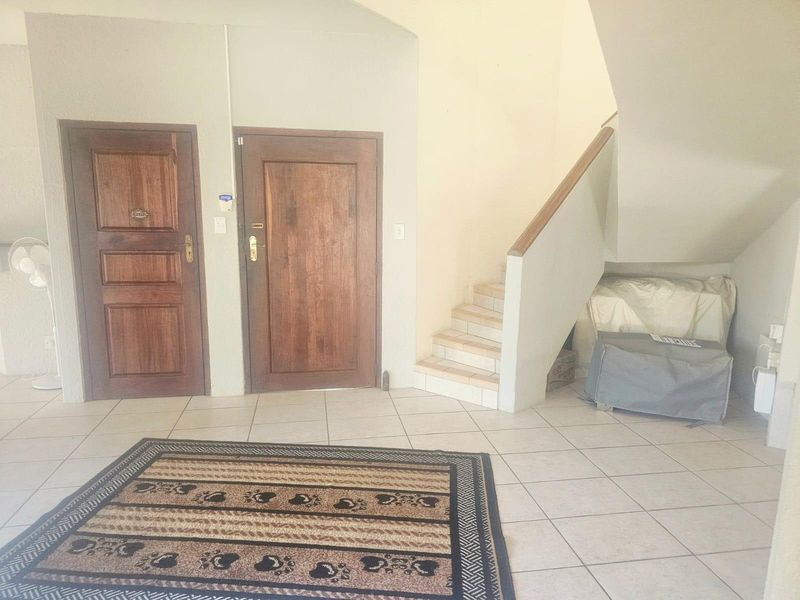 Entrance foyer featuring tiled flooring, two wooden doors, and a staircase leading to the upper level.