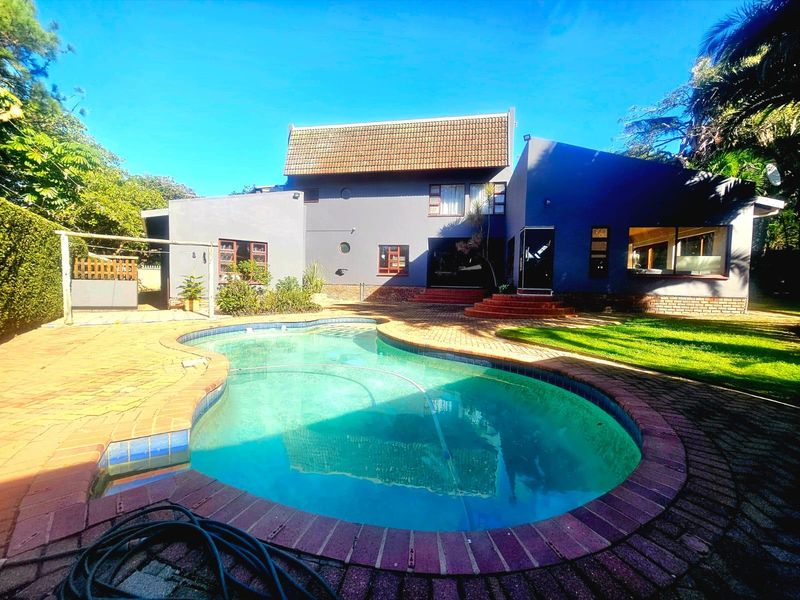 Rear view of the house featuring a swimming pool with brick paving and a multi-level tiled roof structure.