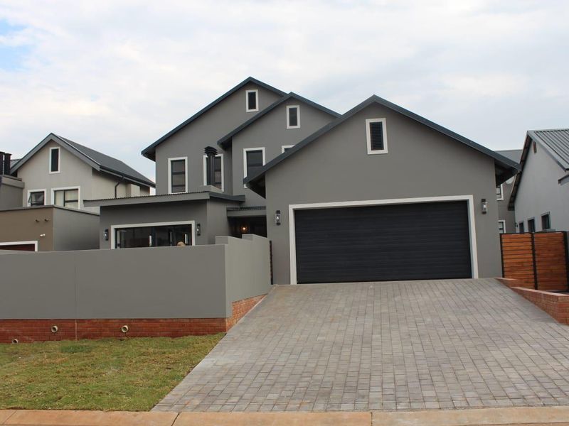 Modern double-storey residential property featuring a paved driveway, double garage, and contemporary grey facade with clean architectural lines.