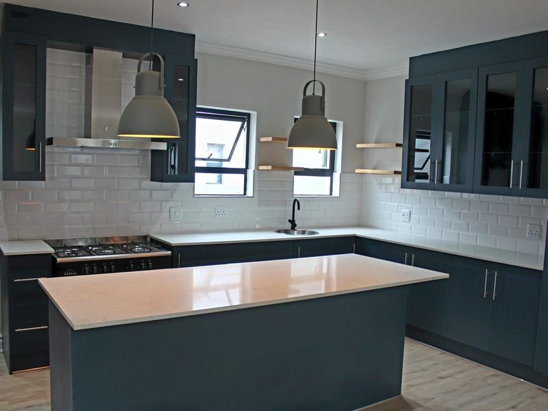 Modern kitchen featuring dark cabinetry, white subway tile backsplash, quartz countertops, a central island, and high-quality integrated appliances.