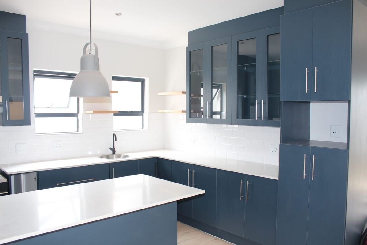 Modern kitchen featuring navy blue cabinetry, white quartz countertops, subway tile backsplash, and a central island with pendant lighting.
