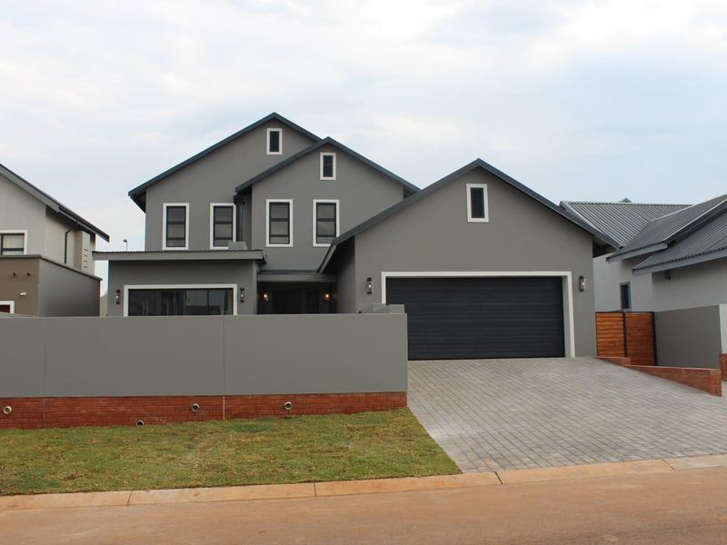 Modern double-story residential home featuring a contemporary grey facade, paved driveway, and integrated double garage.