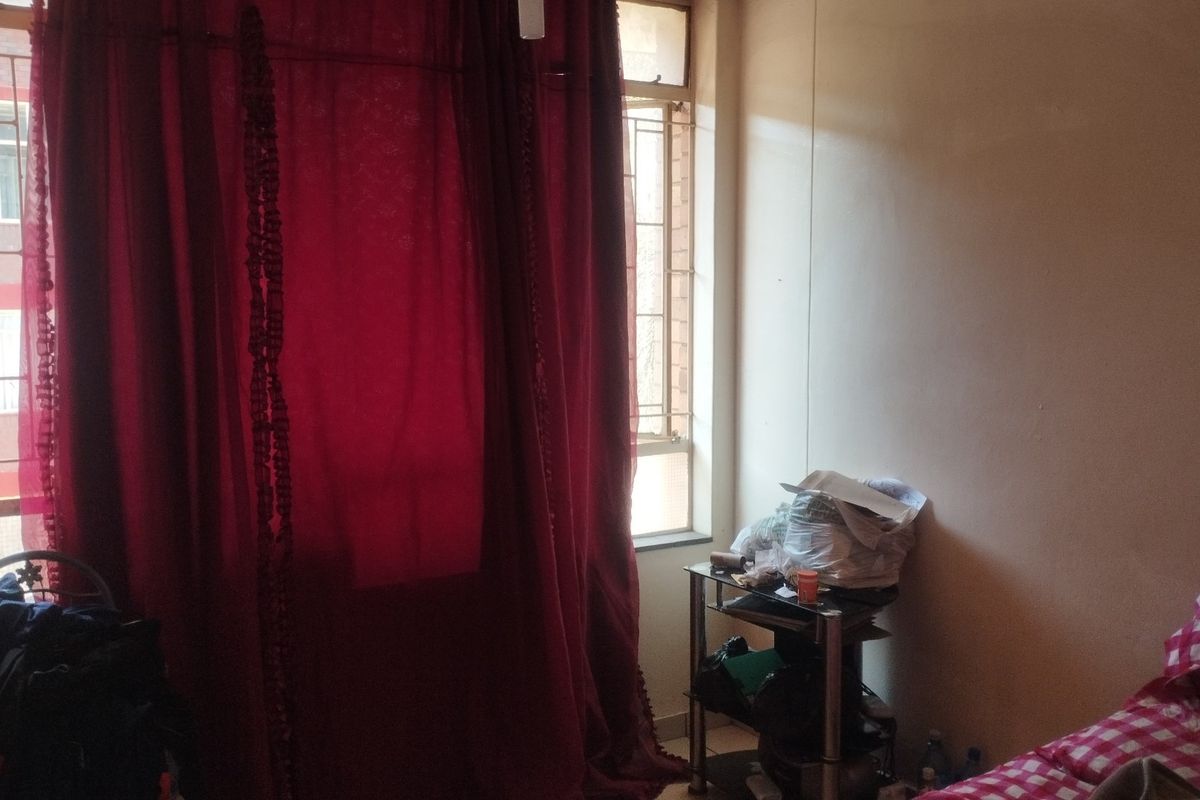 A bedroom featuring large windows with security bars, providing natural light and ventilation.