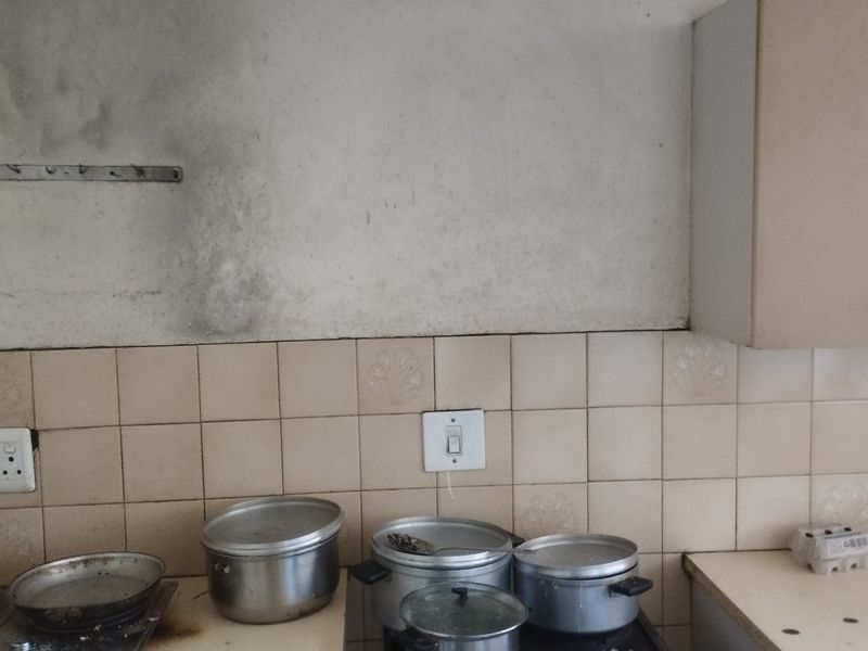 A kitchen area featuring a tiled backsplash and built-in cabinetry, showing significant soot staining on the wall surface above the cooking area.
