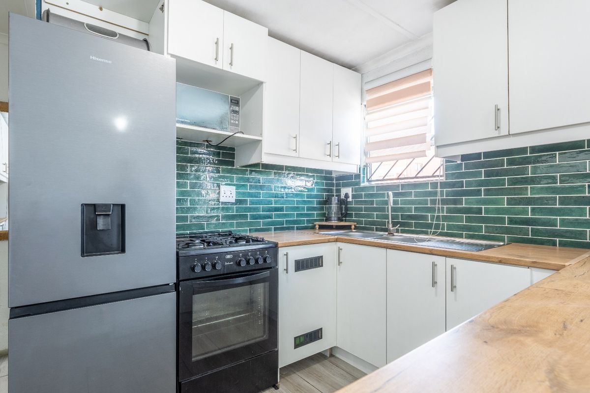 A functional kitchen featuring white cabinetry, wooden countertops, a green subway tile backsplash, and a built-in gas stove with oven.