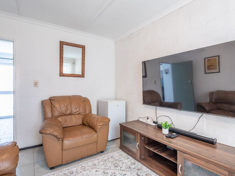 A living room featuring tiled flooring and exposed blockwork walls, with an open transition to the adjacent kitchen area.