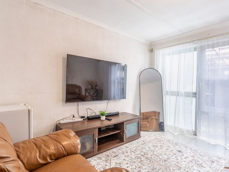 A living room featuring tiled flooring, exposed blockwork walls, and a sliding glass door providing natural light.