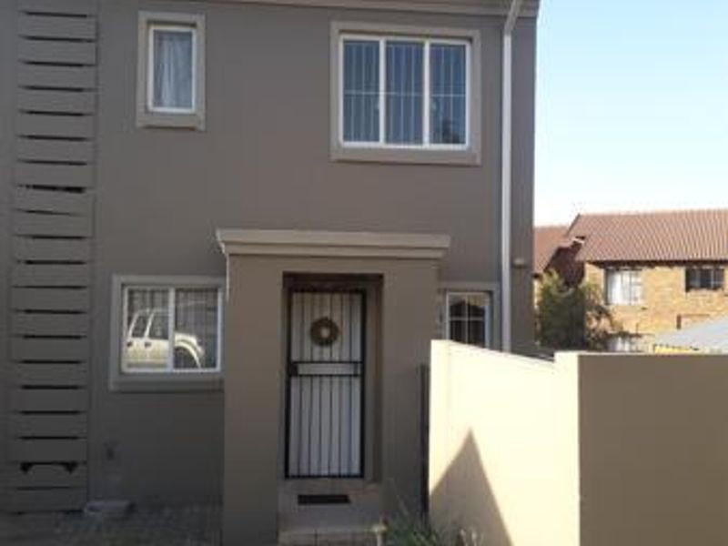 Front elevation of a two-story residential house featuring a secure entrance gate, paved walkway, and boundary wall.