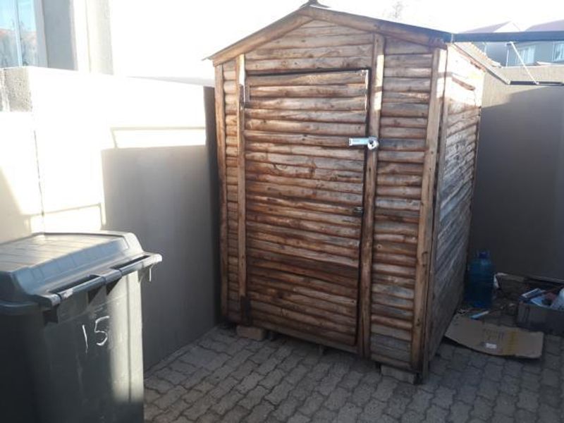 A functional timber garden shed situated in a paved outdoor utility area, providing convenient external storage space.