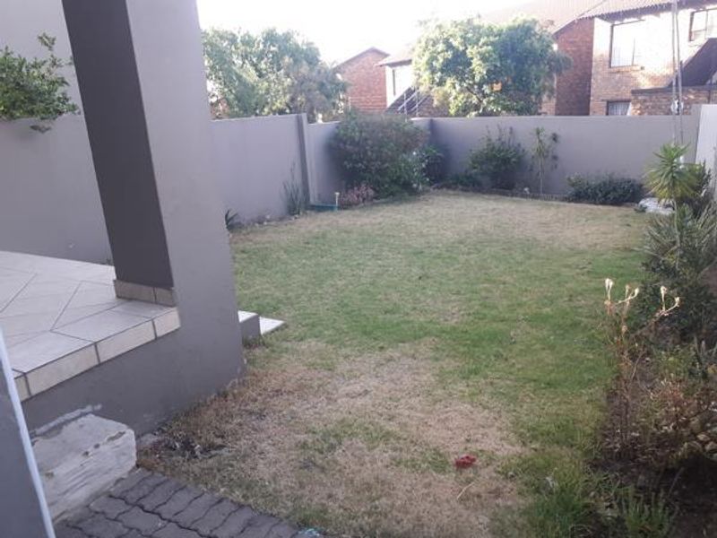 A private rear garden featuring a tiled patio area, paved walkway, and a perimeter wall, offering a blank canvas for outdoor landscaping.