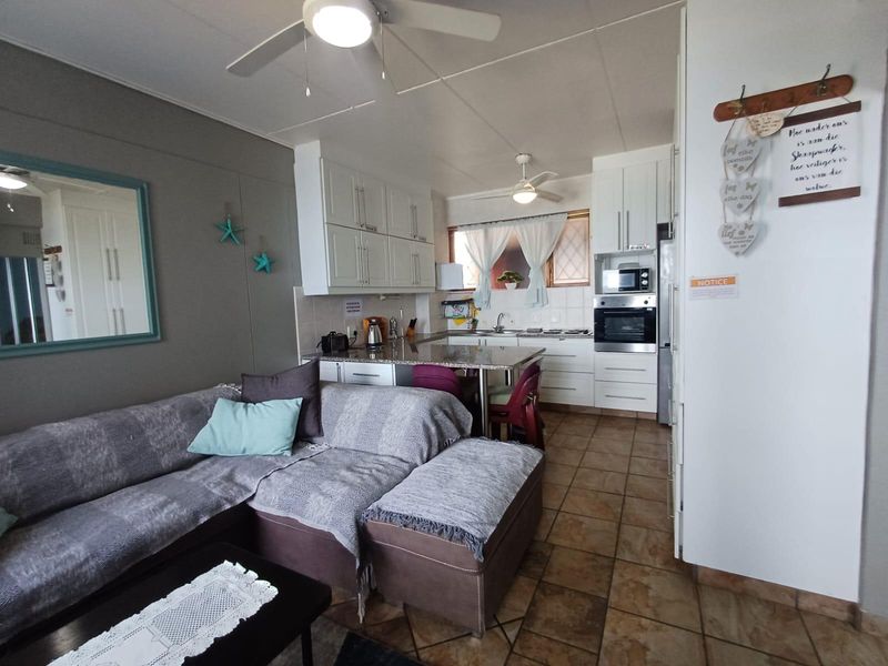 Open-plan living and kitchen area featuring tiled flooring, granite countertops, built-in oven, and cabinetry, creating a functional combined living space.