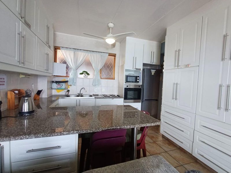 A functional kitchen featuring granite countertops, built-in cabinetry, integrated oven and microwave, and tiled flooring.