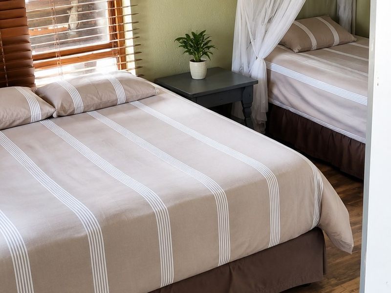 A bedroom featuring wood-look tile flooring and timber venetian blinds, providing a neutral base for interior design updates.