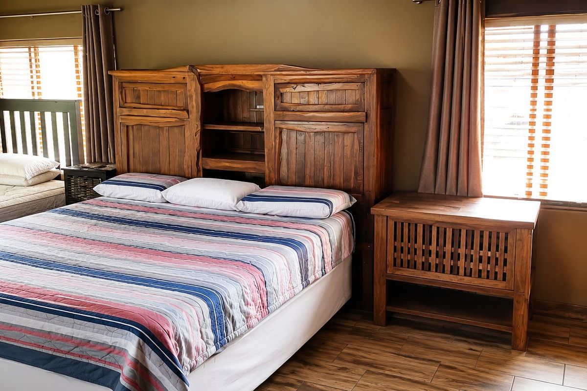 A bedroom featuring wooden flooring, window blinds, and curtain rails, providing a functional space with natural light.