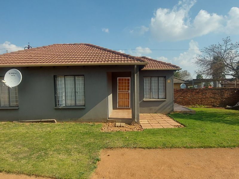 A single-story residential house featuring a tiled roof, security bars on windows, and a front entrance with a security gate.