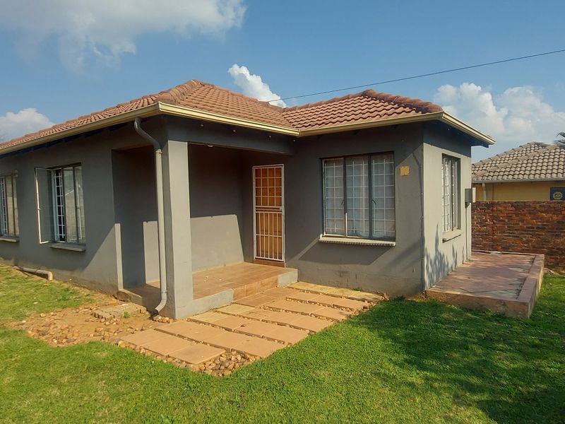 A detached single-story house featuring a tiled roof, security gates, and a paved patio area set within a private garden with brick boundary walls.