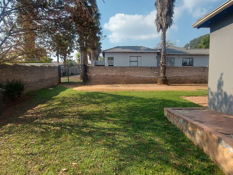 A private rear garden featuring a lawn area, a brick boundary wall, and a tiled patio space.