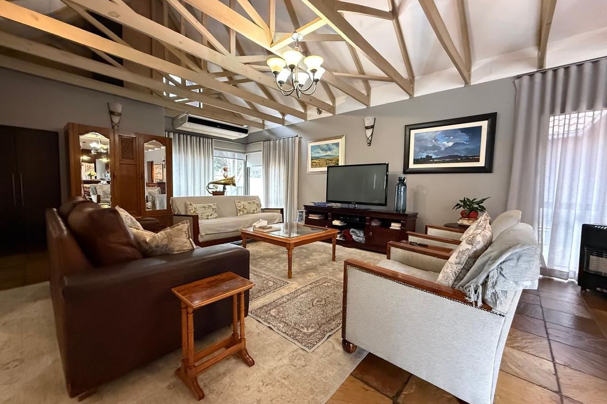 Spacious living room featuring a high vaulted ceiling with exposed timber trusses, terracotta flooring, and a wall-mounted air conditioning unit.