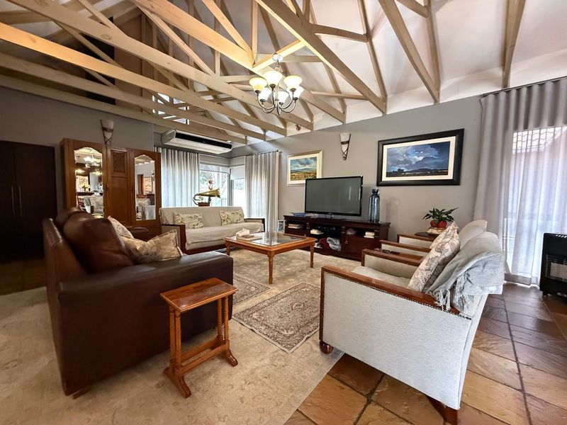 Spacious living room featuring a high vaulted ceiling with exposed timber trusses, terracotta flooring, and a wall-mounted air conditioning unit.