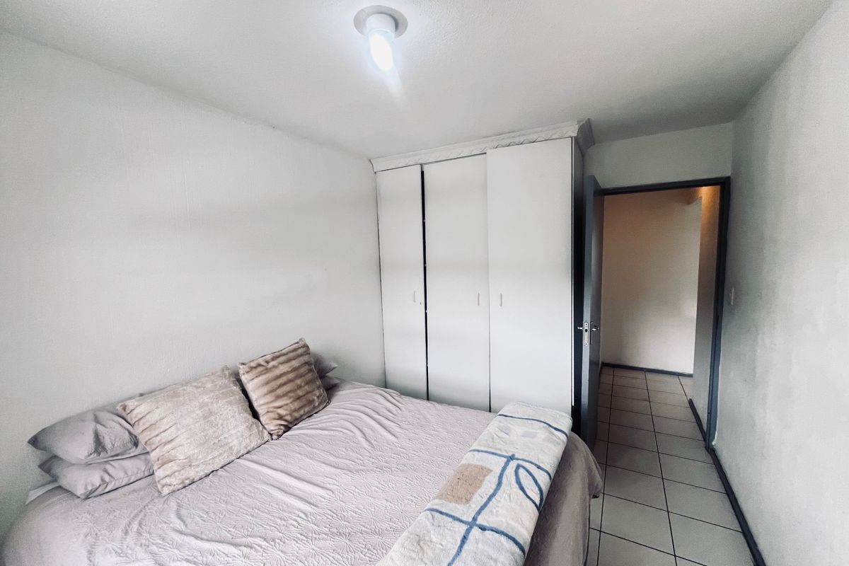 A functional bedroom featuring built-in wardrobes and tiled flooring, providing a clean and simple living space.
